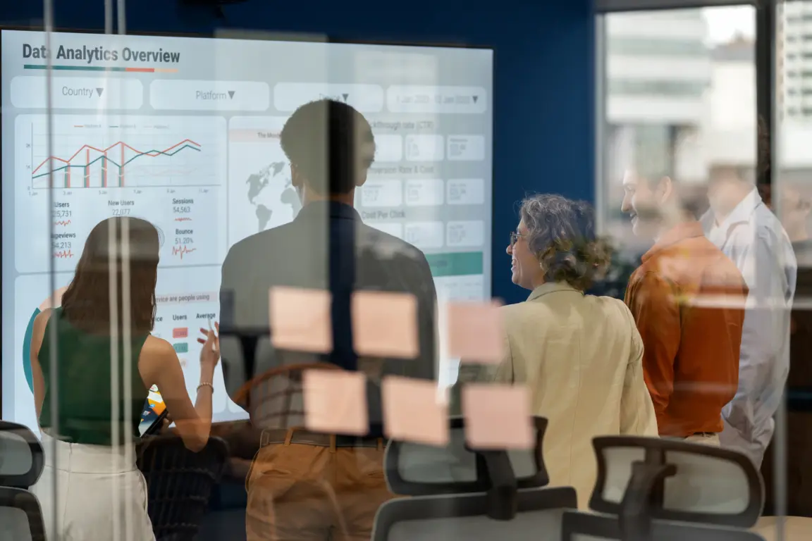 Diverse business development team brainstorming new products and services using a digital display during a business meeting. Business Intelligence and data-driven decisions empowering strategy, growth, and resilience in a modern office. Collaboration and innovation in action.