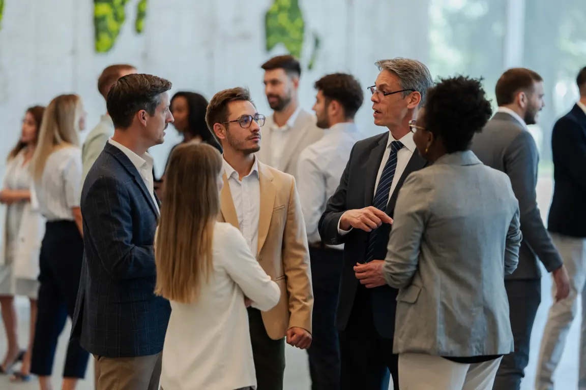 Professionals gathered, engaging in conversations and exchanging ideas at a corporate conference or seminar.
