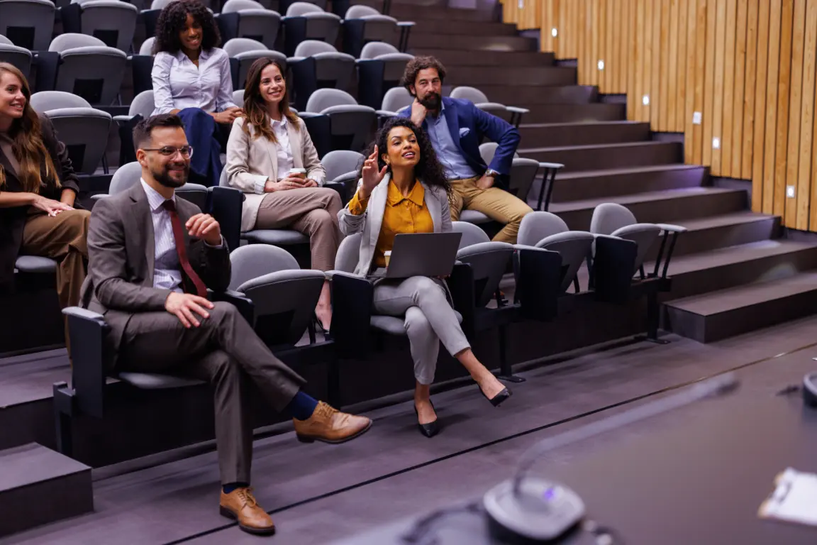 Diverse group of professionals attending conference, learning, and participating in an auditorium.