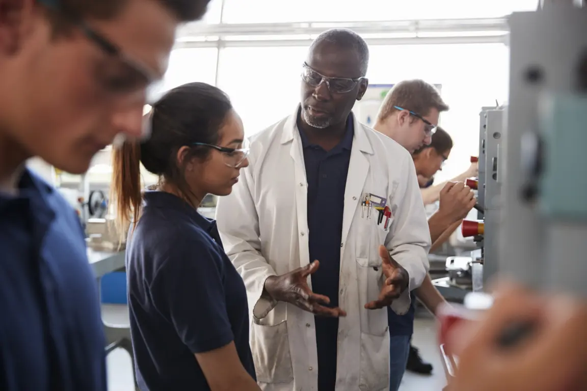 Engineer instructing female apprentice at a drill press.
