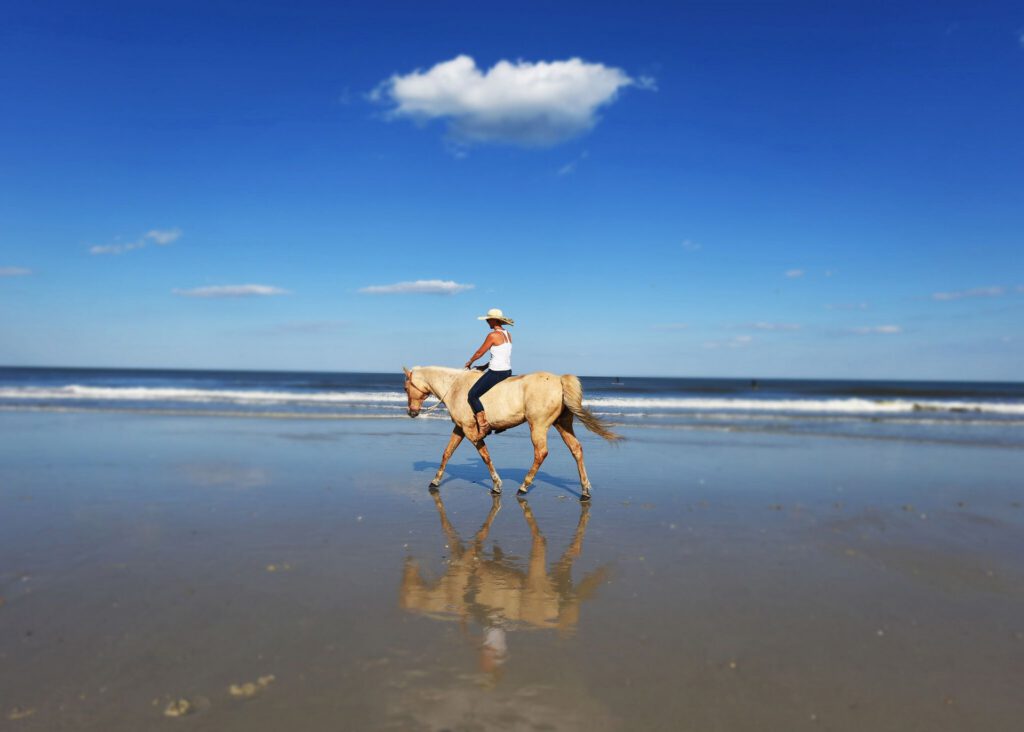 A woman horseback rides on the Amelia Island beach.